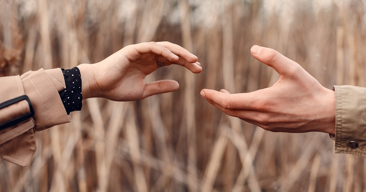 Nem oldhatsz meg mindent mások helyett: segítek, de határokkal Egy nő és egy férfi egymás felé nyújtja a kezét, de nem érik el egymást
