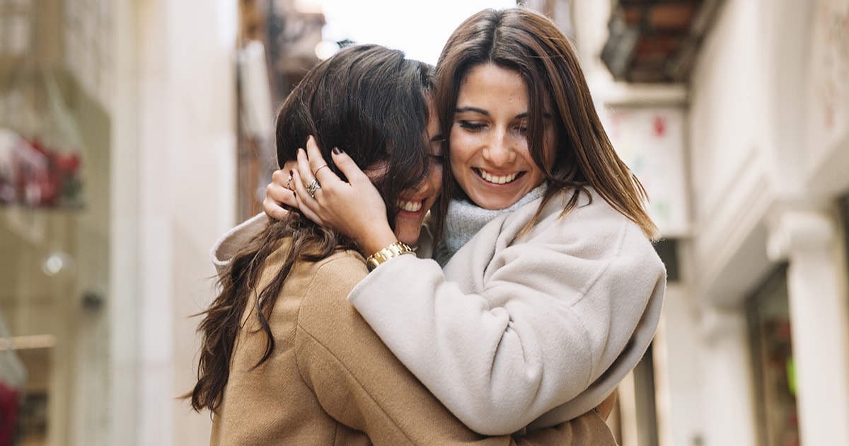 Az ölelés típusai és jelentésük Két barátnő boldogan átöleli egymást szorosan az utcán