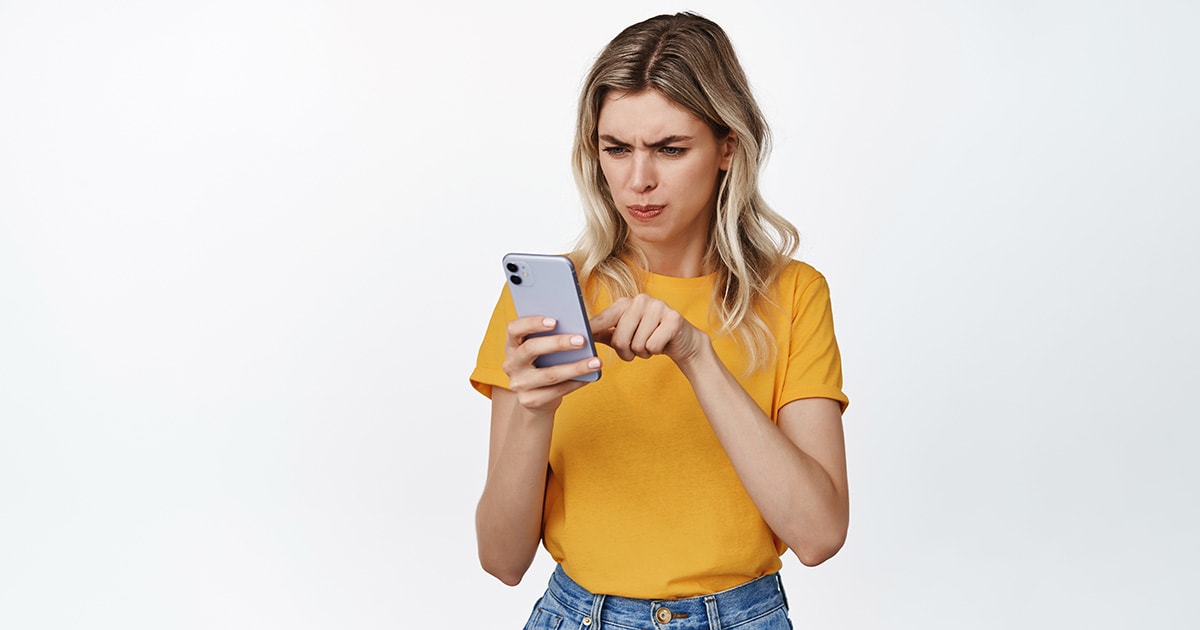 Tiltás–oldás: a digitális kor ajtócsapkodása Egy ideges nő, aki a telefonját szorítja és megnyomja a tiltás gombot a Facebookon és a többi közösségi felületen